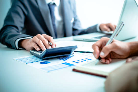 Man in suit using a calculator and computer